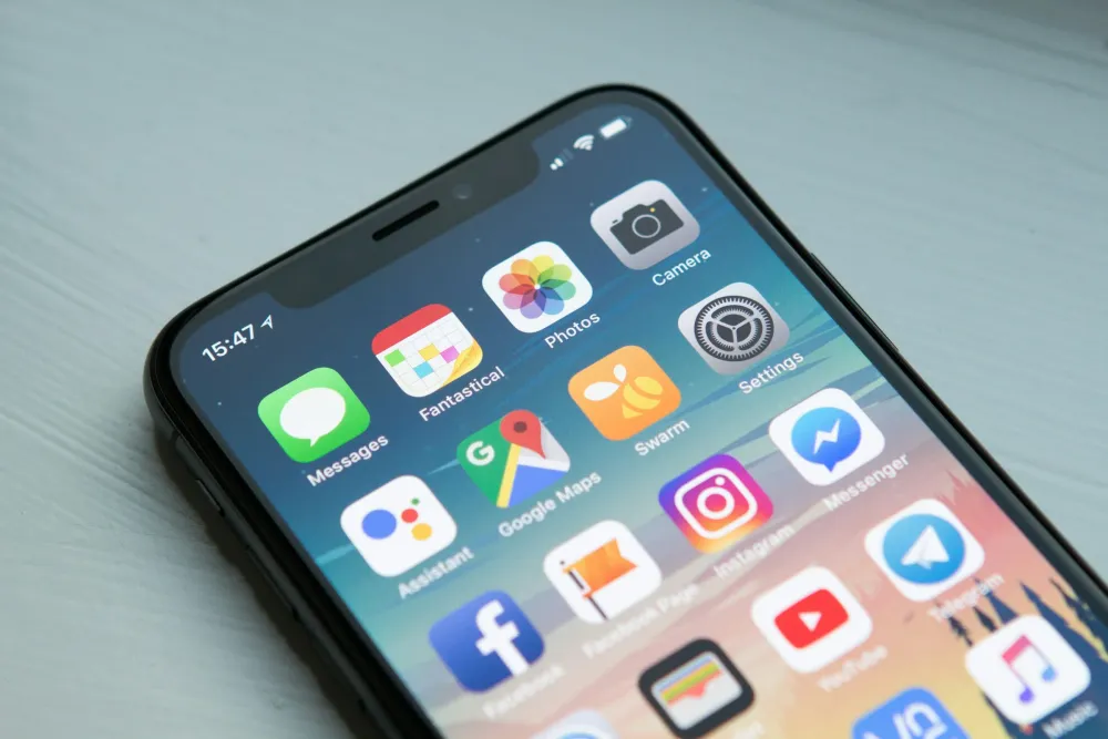 Açılı yakın çekimde bir telefon ana ekranı, uygulama simgeleriyle dolu.